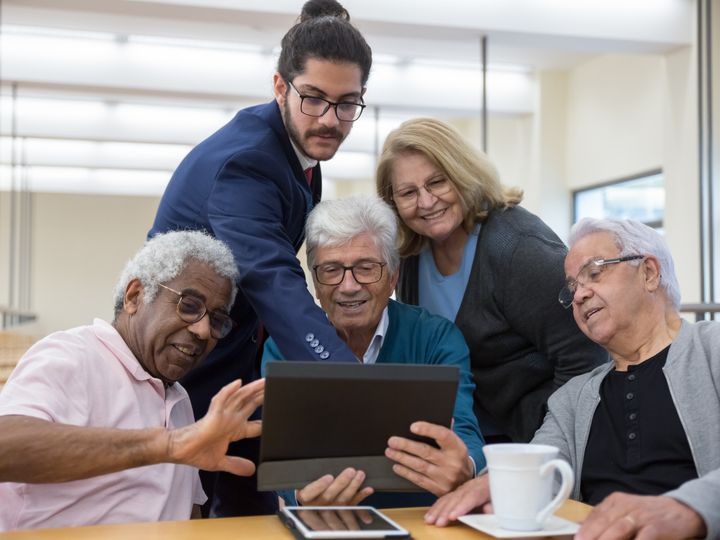 Adultos mayores revisando información en una tableta con un asesor