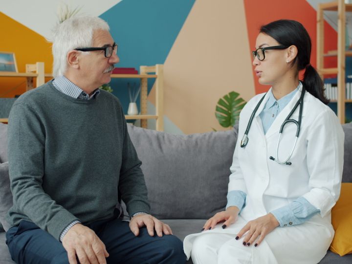Doctora en consulta con un paciente mayor