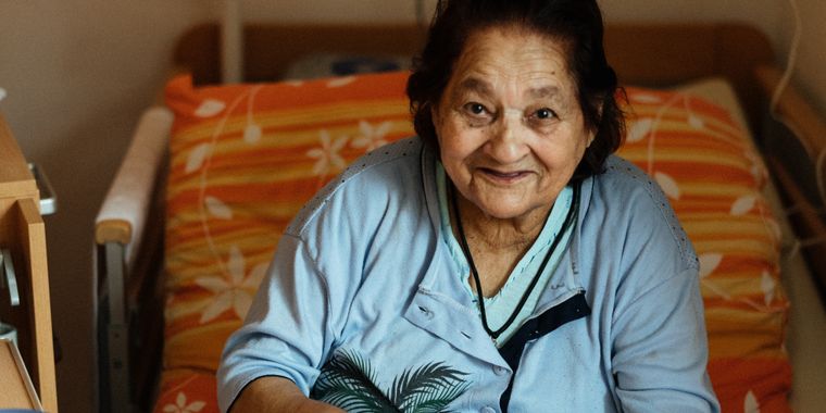 Señora mayor sonriendo en su cama de hospital