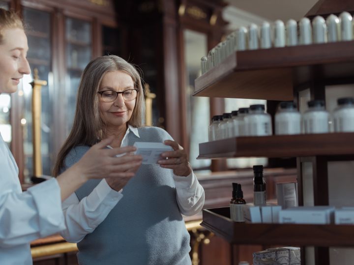 Agente ayudando a una señora mayor en una farmacia