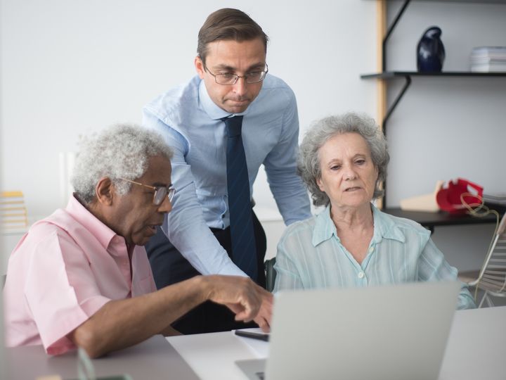 Agente revisando opciones en una computadora con una pareja mayor